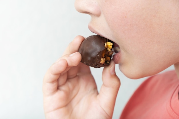 Garçon mangeant des bonbons au chocolat artisanaux sains avec des noix