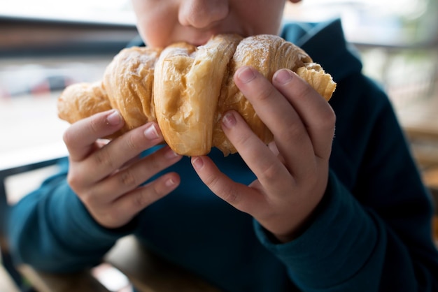 un garçon mangeant un croissant en gros plan photo recadrée