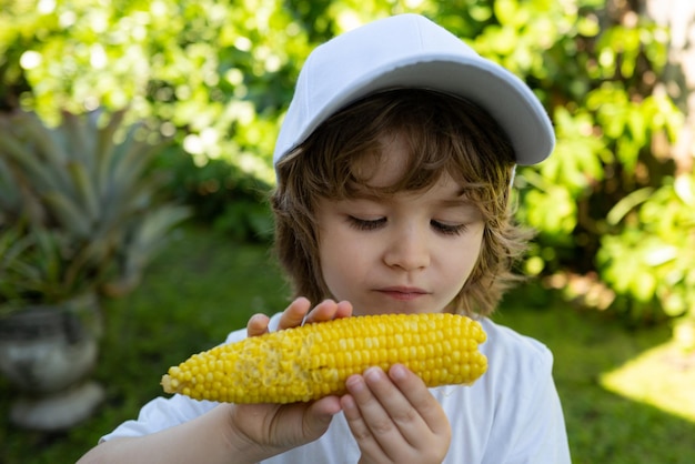 Garçon mangeant des enfants de maïs avec des légumes maïs bio frais