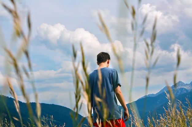 Photo garçon marchant dans les montagnes avec de l'herbe