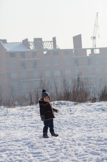 Garçon marchant en hiver et regardant la grue sur un chantier de construction