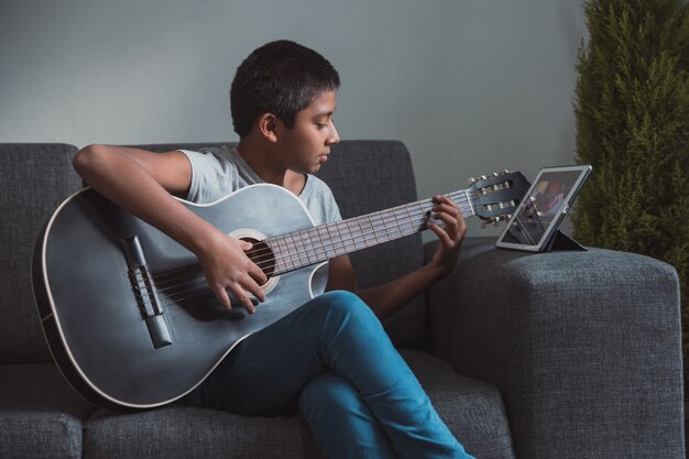 Un garçon mexicain prend des cours de guitare à la maison en raison du verrouillage du coronavirus et de l'enseignement à domicile