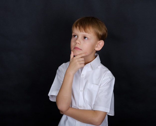 Photo garçon mignon d'apparence européenne dans une pose réfléchie. isoler sur un noir