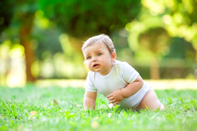 Garçon mignon bambin en Body blanc assis sur l'herbe