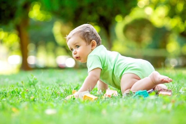 Garçon mignon bambin en Body vert assis sur l'herbe
