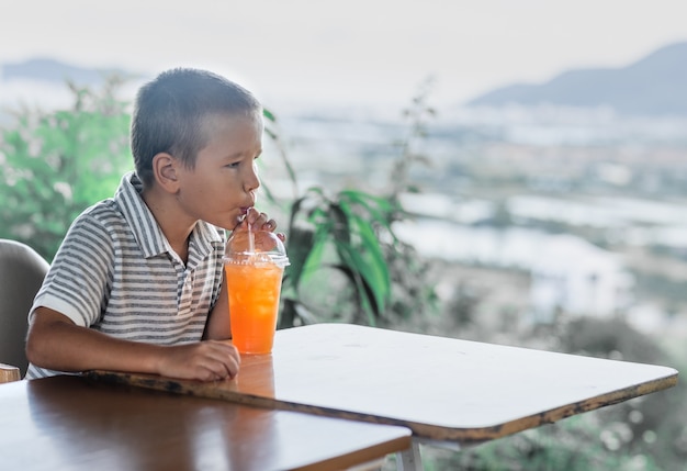 Garçon mignon, boire du jus dans un café en plein air