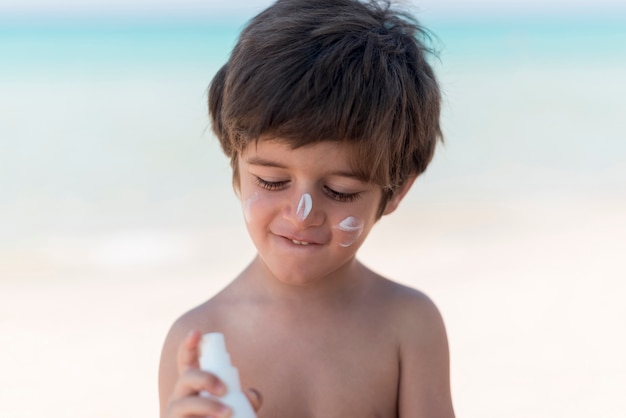 Garçon Mignon Avec De La Crème Solaire à La Plage