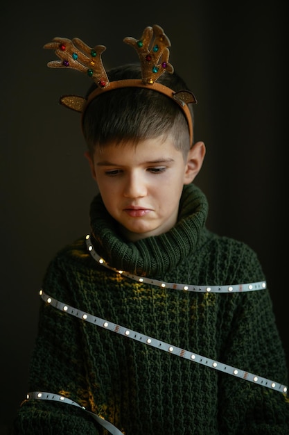 Un garçon mignon dans un pull vert et des cornes de cerf est triste