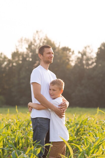 Un garçon mignon embrasse son père au coucher du soleil T-shirts blancs