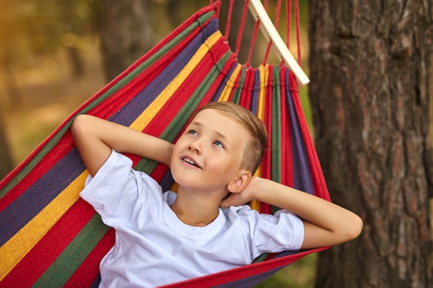 Le garçon mignon est allongé dans un hamac coloré. L'enfant monte dans un hamac. Notion de loisirs