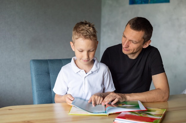 Un garçon mignon est assis à la table avec son père et regarde un livre sur les serpents