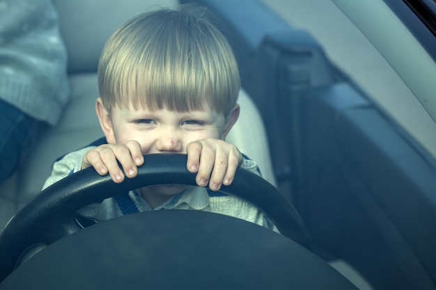 Un garçon mignon fait semblant de conduire une voiture