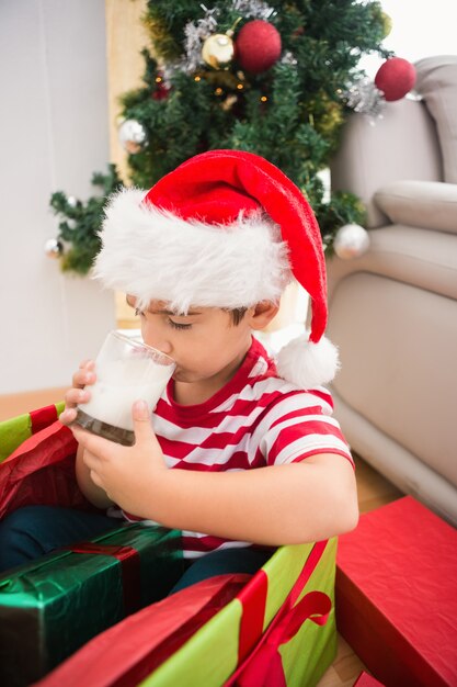 Garçon mignon en gros cadeau de Noël boire du lait