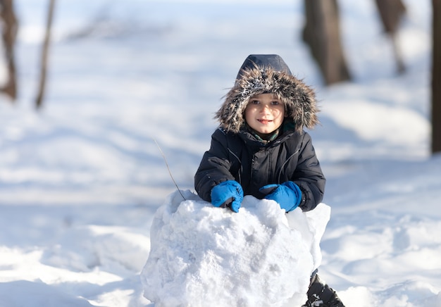 Garçon mignon jouant avec de la neige dans le parc d'hiver