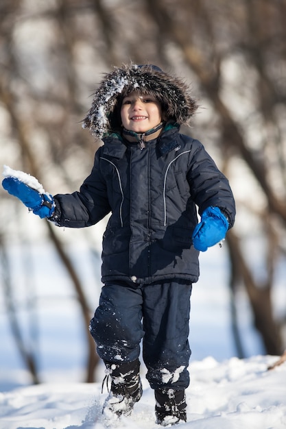 Garçon mignon jouant avec de la neige