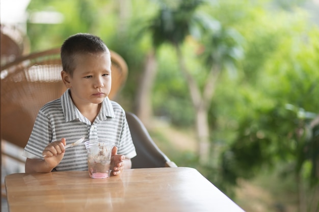 Garçon mignon, manger des glaces dans un café en plein air