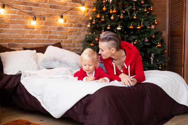 Garçon mignon et mère sur le lit près de l'arbre de Noël. Noel, vacances et concept d'enfance