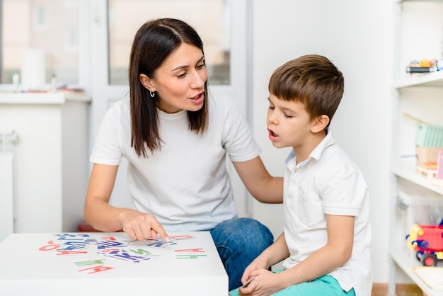 Un garçon mignon avec un orthophoniste apprend à prononcer les mots et les sons des lettres