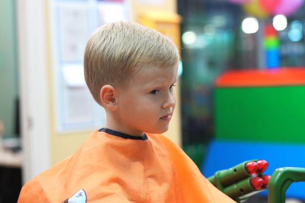 Photo un garçon mignon qui détourne le regard assis au barbier.