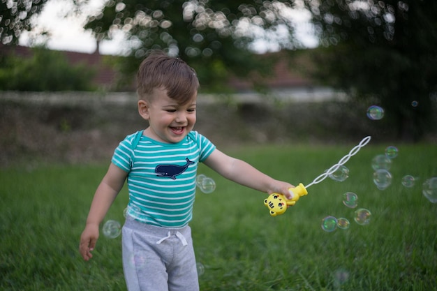 Un garçon mignon qui joue avec une baguette à bulles sur le terrain.