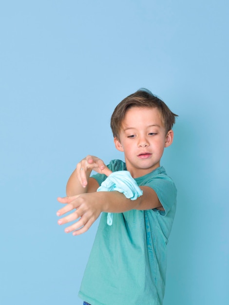 Un garçon mignon qui joue avec de la boue sur un fond bleu.