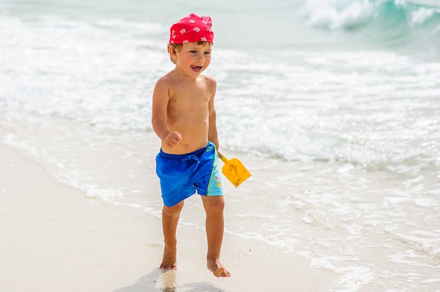 Garçon mignon s'amusant sur la plage.