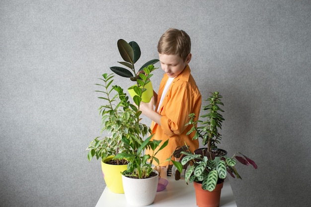 Un garçon mignon s'occupe des plantes d'intérieur Vérifie le niveau d'humidité
