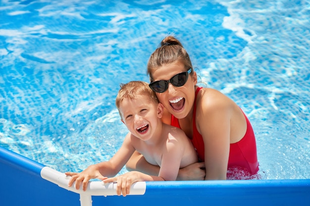 garçon mignon avec sa mère jouant dans une piscine d'eau pendant l'été