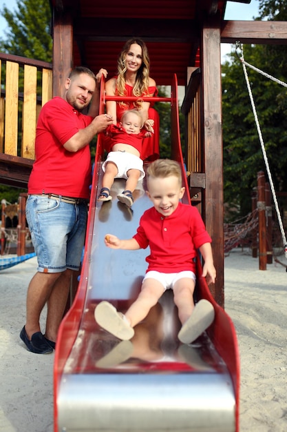 Le garçon monte sur une glissière en bois avec sa famille