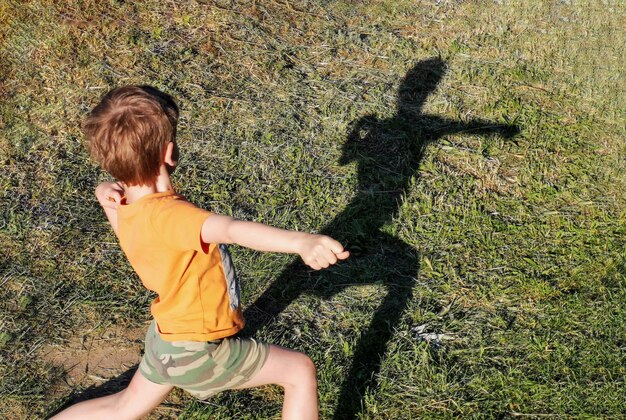 Le garçon montre ses muscles L'ombre du garçon Le garçon pose Les enfants font du sport Les enfants font de l'exercice