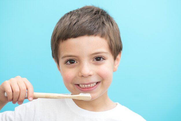 Garçon montrer les dents avec une brosse sur fond bleu