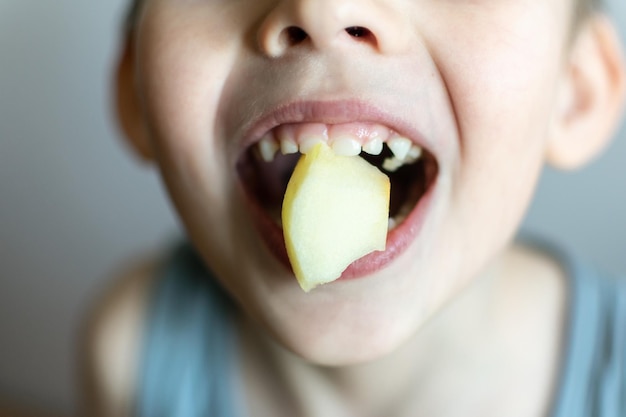 Un garçon avec un morceau de pomme dans la bouche