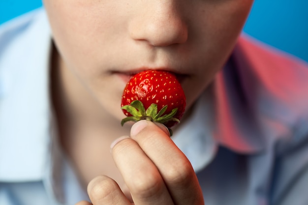 Un garçon mordant des fraises rouges