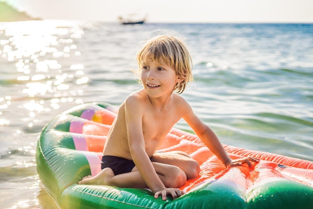 Le garçon nage dans la mer sur un matelas gonflable