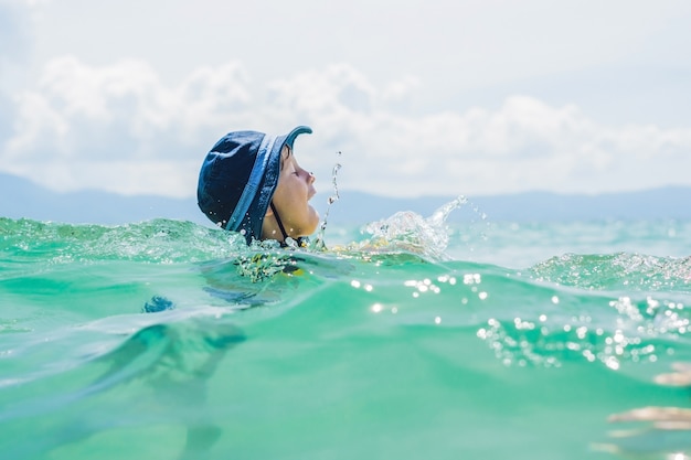 Le garçon nage dans la mer.