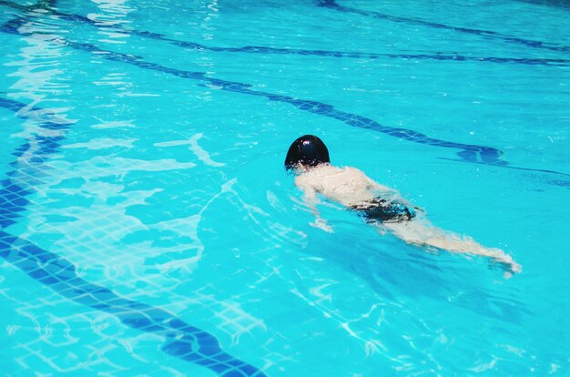 Un garçon nageant dans une piscine.