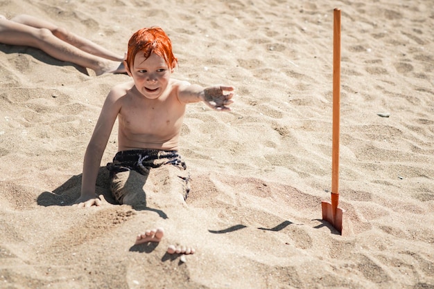 Garçon de neuf ans sur la plage creuse dans le sable