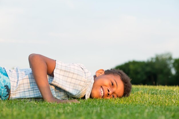 Garçon noir allongé sur l'herbe et souriant.