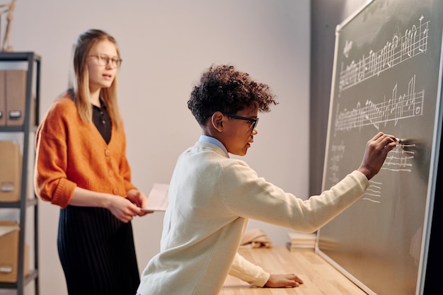 Un garçon noir écrit sur le tableau à la leçon de musique.