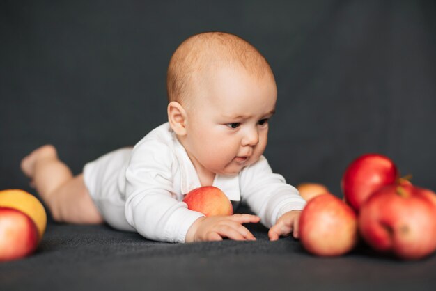 Garçon nouveau-né couché avec des pommes. Petit enfant caucasien