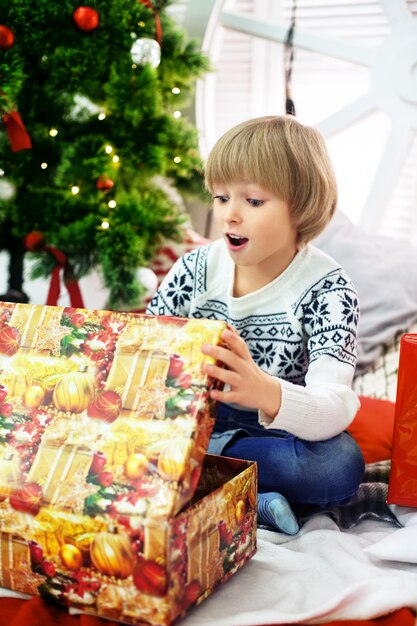 Garçon ouvre une boîte-cadeau le jour de Noël