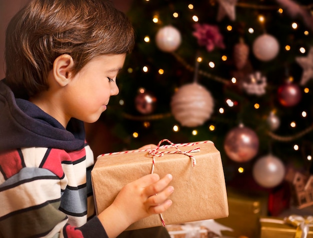 garçon ouvre un cadeau sous le sapin