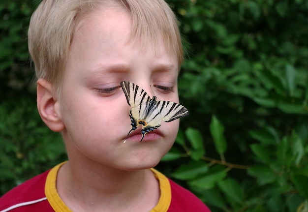 un garçon avec un papillon sur le nez