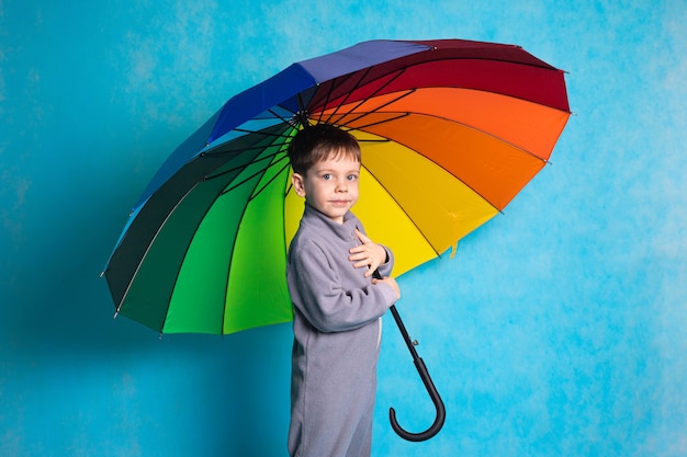 Un Garçon Avec Un Parapluie Coloré Sur Fond Bleu