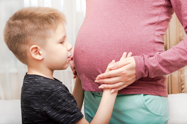 Le garçon parle au ventre de femme enceinte de sa mère