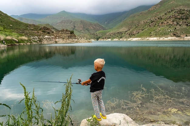 Un garçon pêche sur le lac de montagne Gizhgit dans la région de KabardinoBalkaria Elbrus en Russie juin 2021