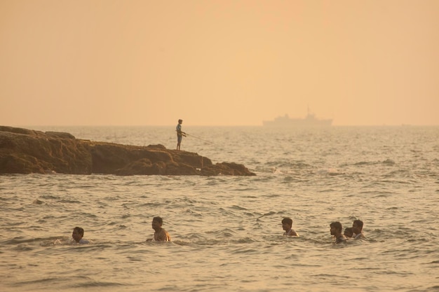 Garçon Pêcheur Et Un Grand Navire Dans Le Brouillard Derrière Plusieurs Hommes Se Baignent Dans L'eau