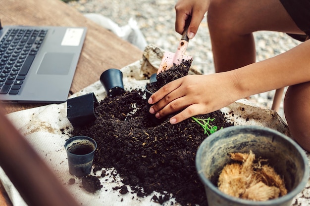 Un garçon pellette de la terre dans des pots pour préparer les plantes à planter le concept d'activités de loisirs