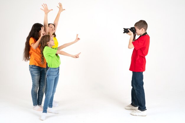 Un garçon photographe prend des photos de trois jolies filles sur blanc dans le studio