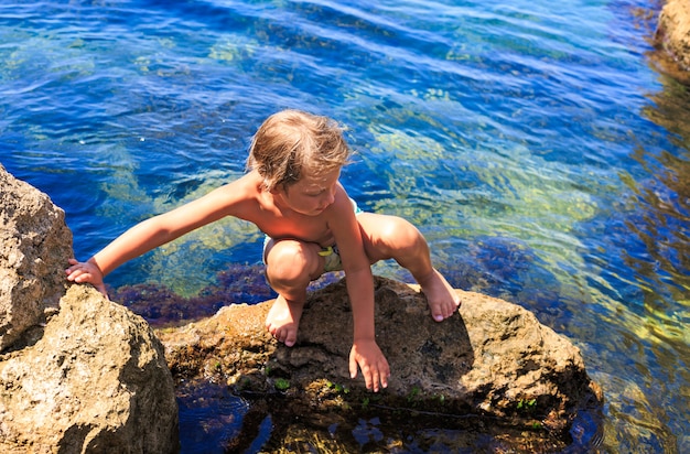 Garçon sur les pierres de la plage.